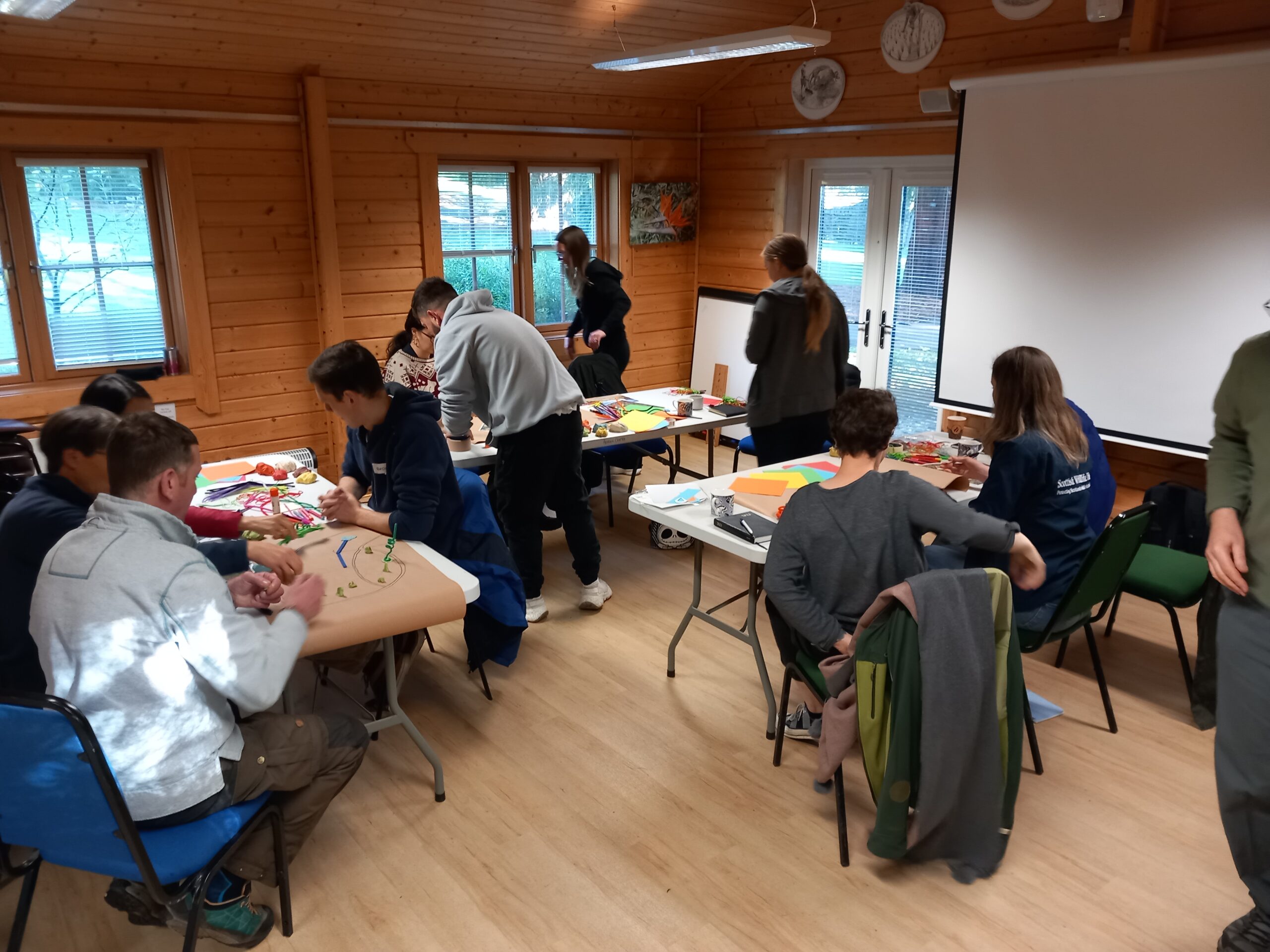 People sitting around tables in a wood-panelled room, working on group projects